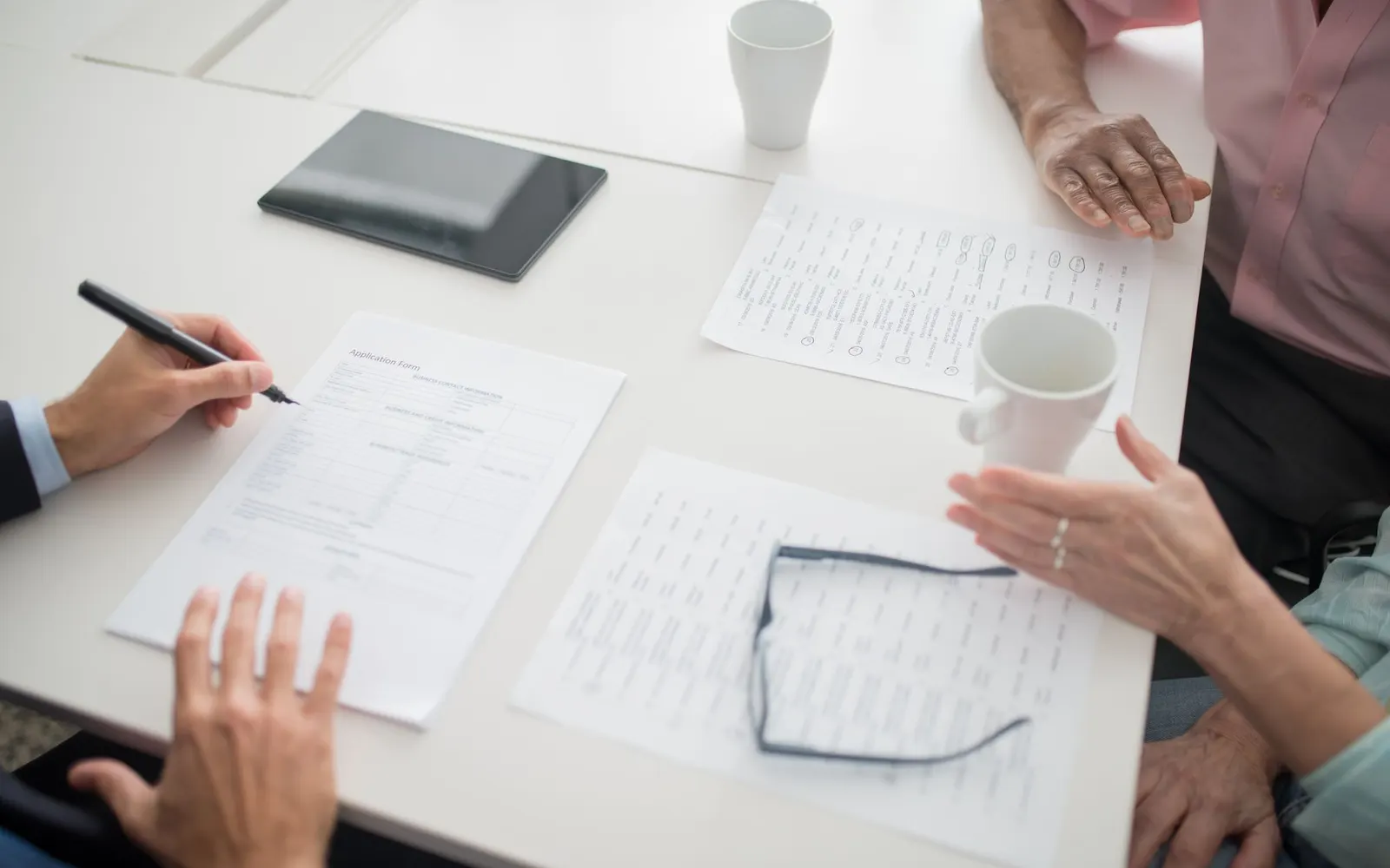 Hands and papers around a table during a work discussion.