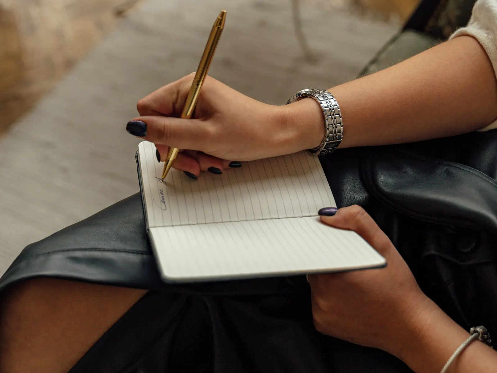 Hands writing notes in a notebook.
